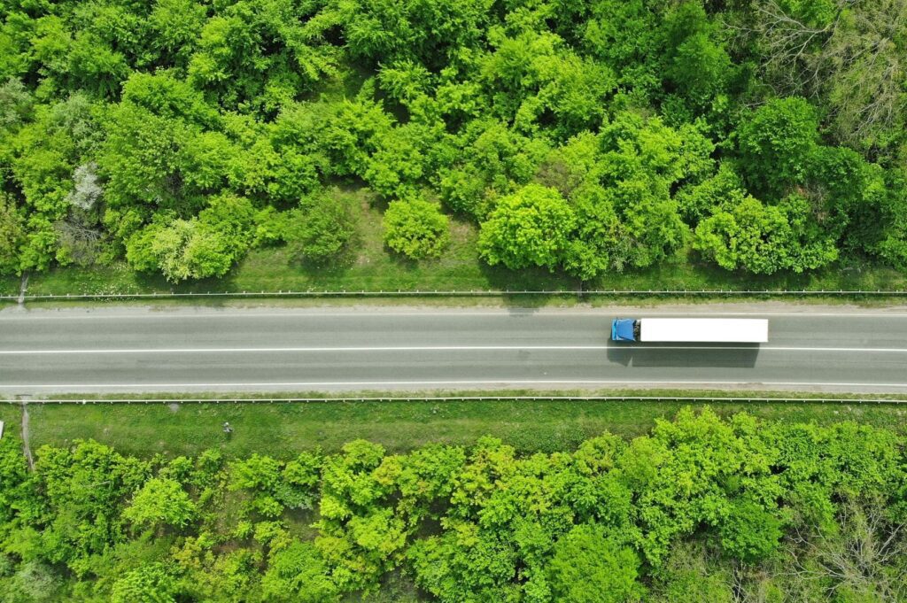 Truck driving through the forest to it's next delivery.