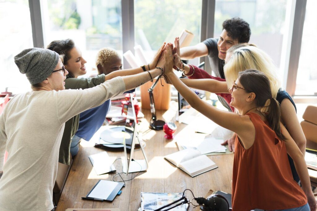 The team at their desks giving each other a high five.