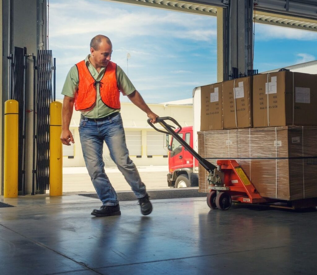 Workers restacking pallets and rewrapping loads at OLIMP Tijuana facility.
