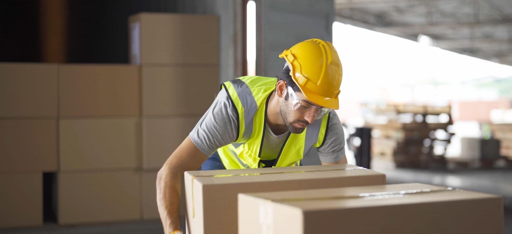 Warehouse worker transferring inventory between storage areas in a modern logistics facility, representing efficient 4PL supply chain operations