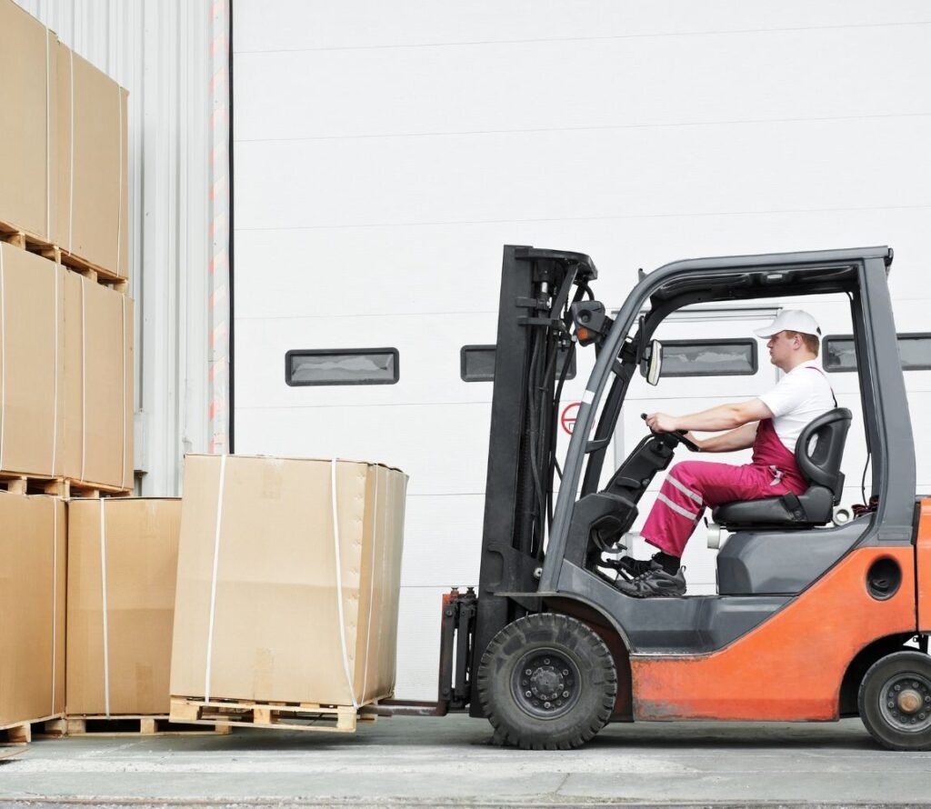 Technician reworking and shrink-wrapping pallets at OLIMP Warehousing Hopkinton to prepare freight for safe delivery.