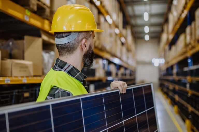 Warehouse workers carefully handling solar panels during the logistics process.