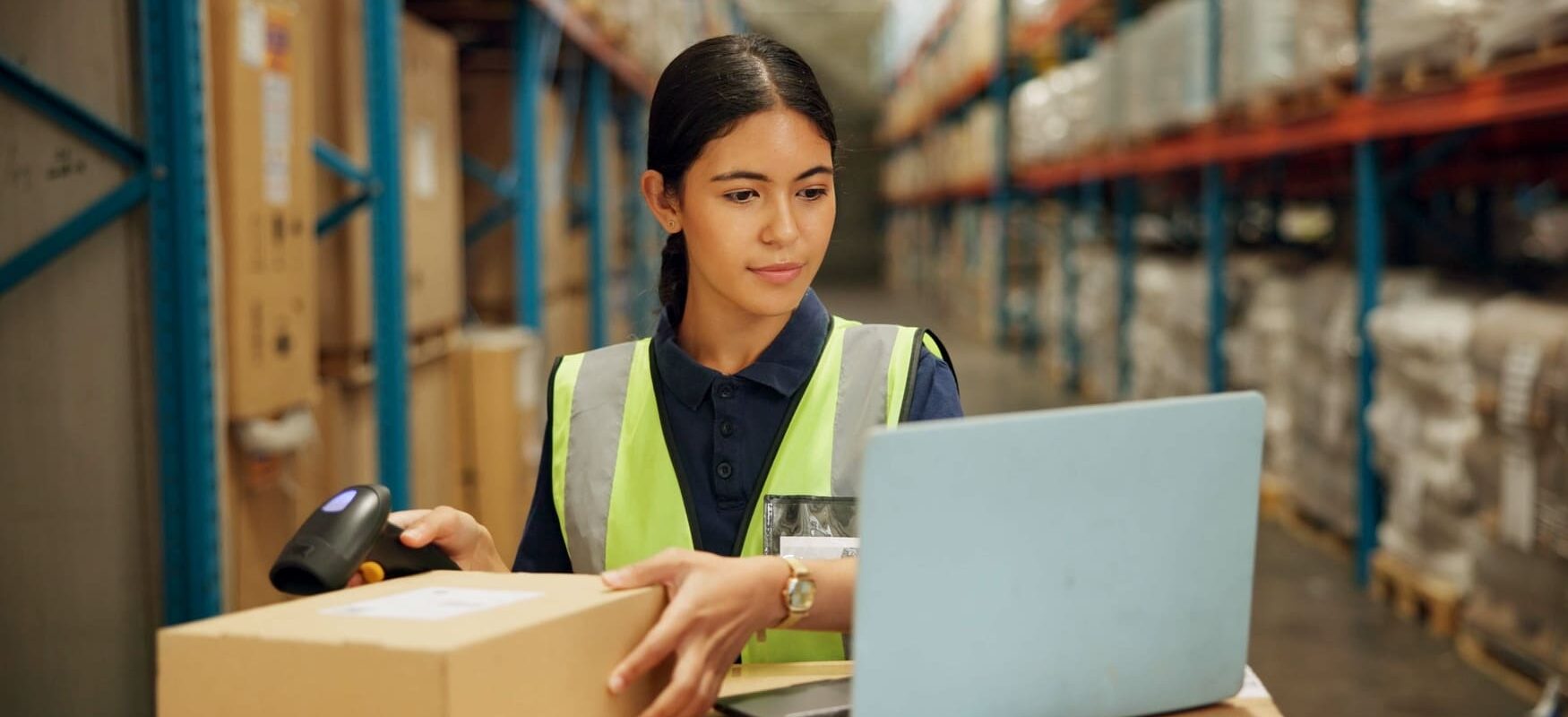 A warehouse worker uses inventory management software – part of a comprehensive logistics service. Professional logistics providers use skilled staff and technology to manage storage and shipments efficiently.