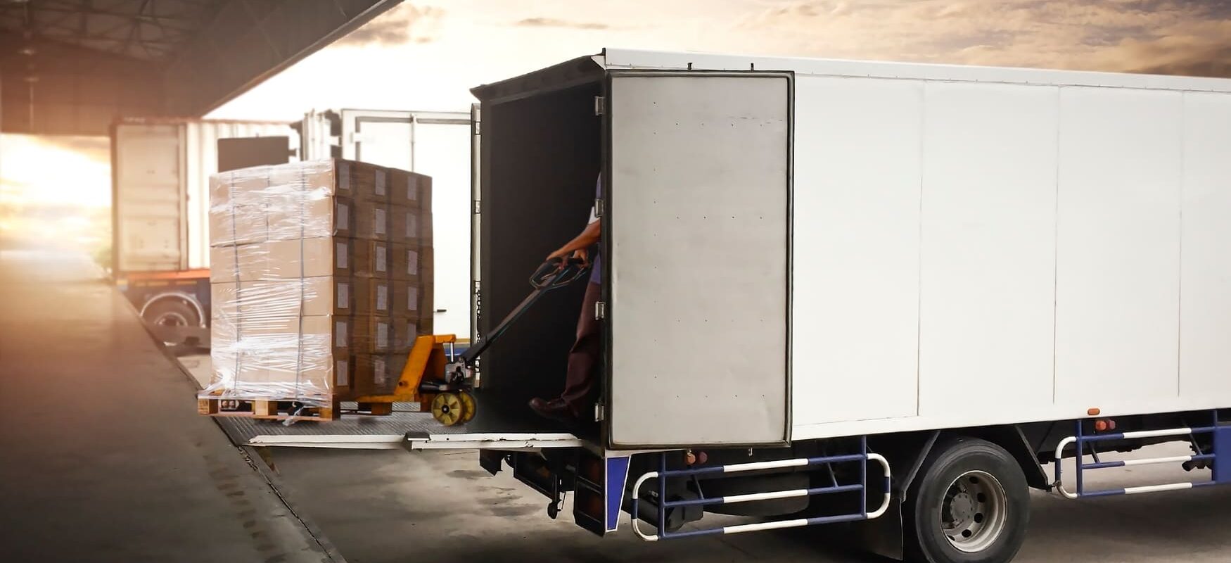 Freight consolidation in action at a warehouse loading dock with pallets of boxes ready to be loaded into a semi-trailer truck.