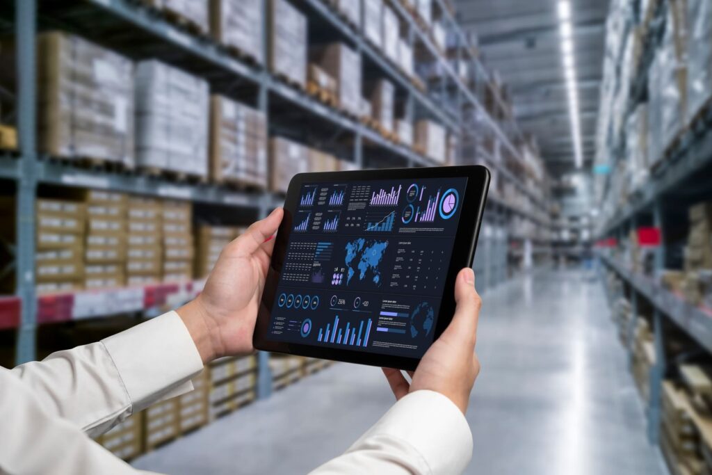 Person using a tablet with warehouse management system dashboard in a modern commercial warehousing facility
