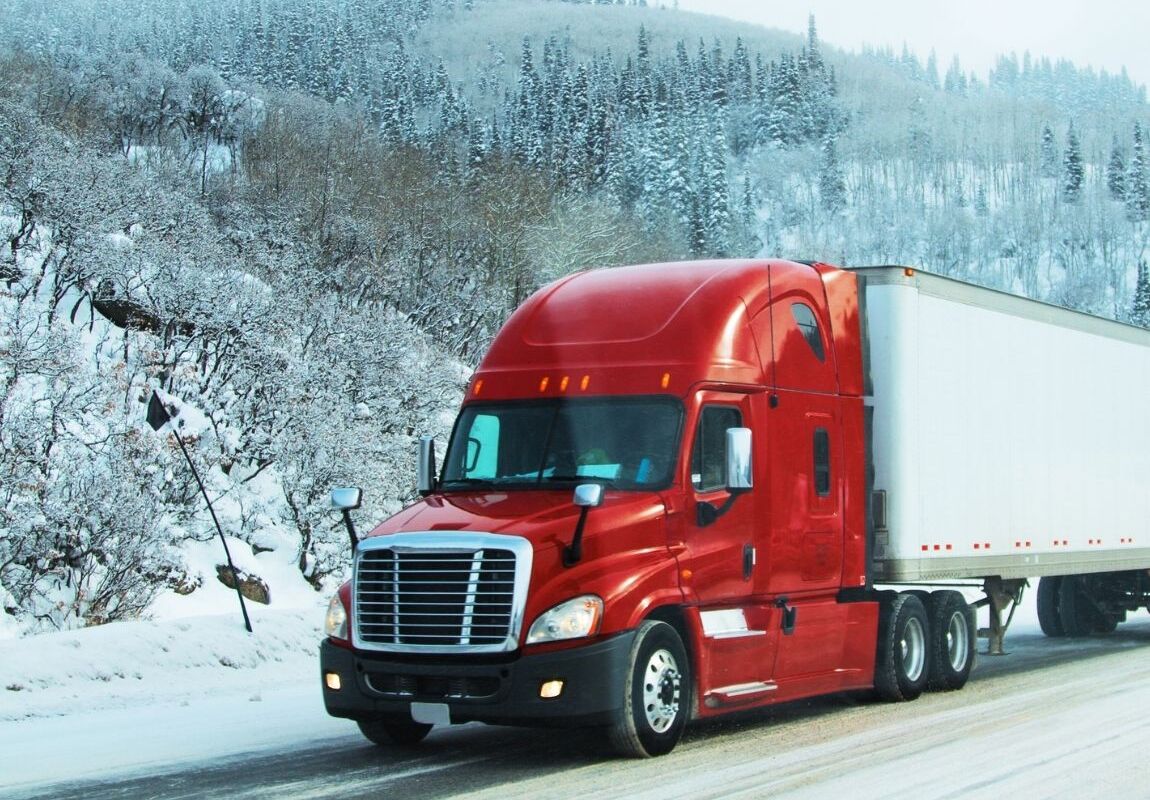 Freight truck driving on a snowy highway during winter shipping conditions in the USA.
