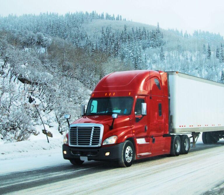 Freight truck driving on a snowy highway during winter shipping conditions in the USA.