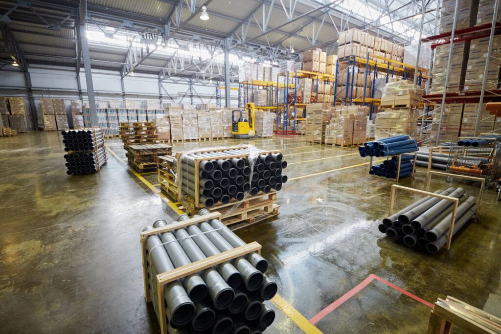 Manufacturing equipment and stacked pallets in a secure industrial storage facility.