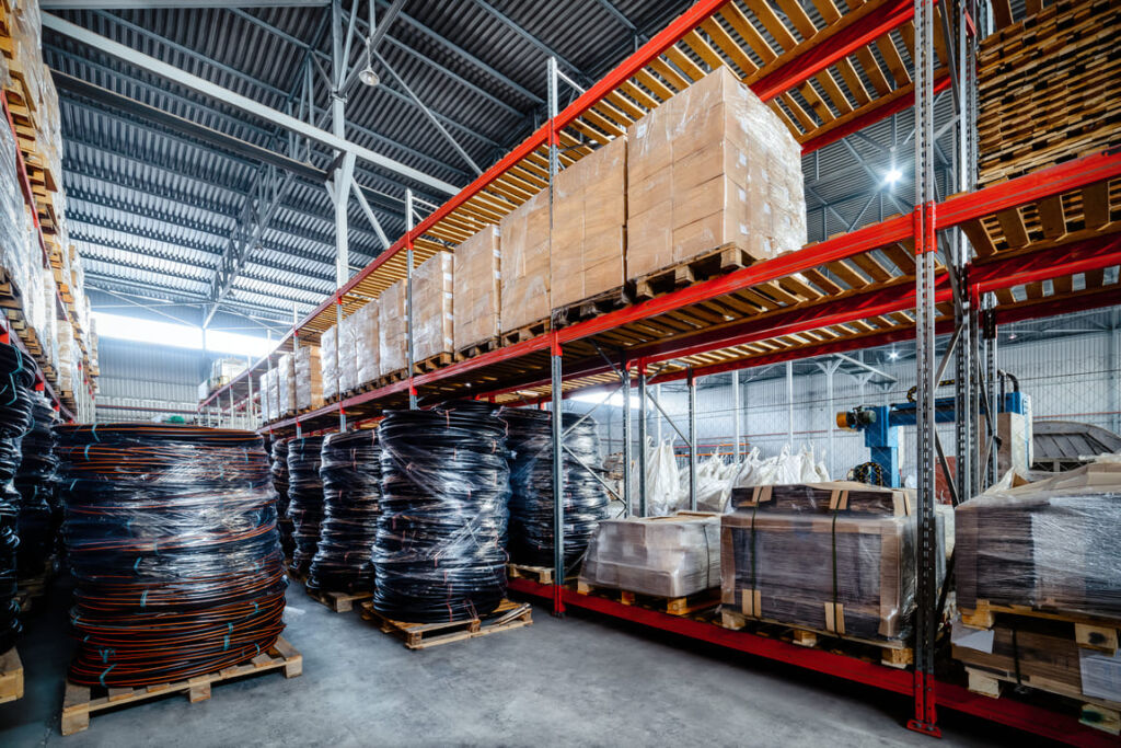 Warehouse exterior showing loading docks, trucks and signage highlighting OLIMP’s nationwide coverage.